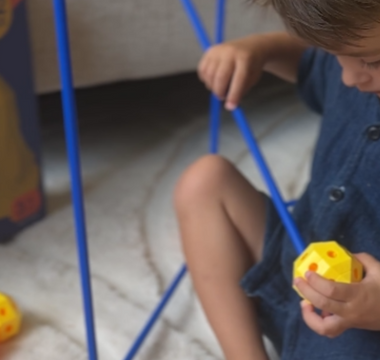 Kind dat vrolijk experimenteert met constructiespeelgoed en zo creativiteit en probleemoplossend vermogen ontwikkelt.